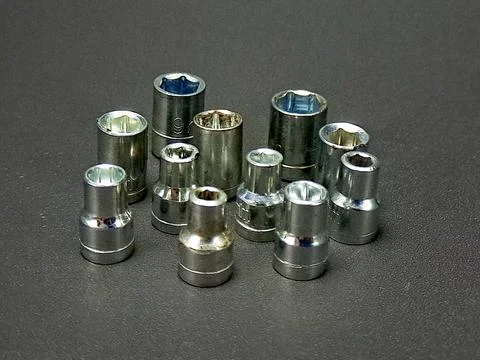 Group of socket wrench heads are displayed on a textured gray surface, refl.. Stock Photos