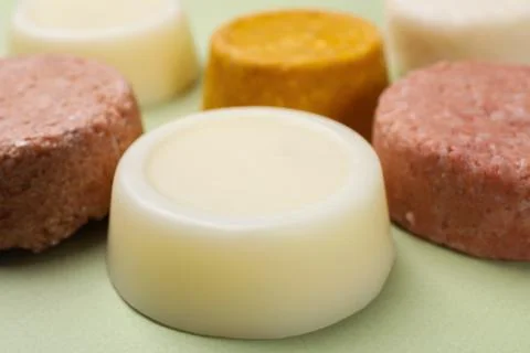 Group of solid shampoo bars on green table, closeup. Hair care Foto stock