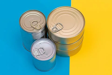 A Group of Stacked Tin Cans on Split Blue and Yellow Background Stock Photos
