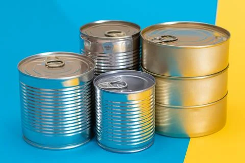 A Group of Stacked Tin Cans on Split Blue and Yellow Background Stock Photos