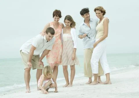 Group standing on the beach, man bending over to talk to daughter Stock Photos