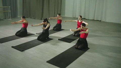 A group stretching class on mats with a trainer helps develop body flexibility. Video stock 243561929