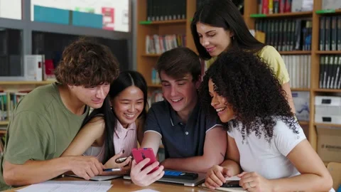 Group of student friends having fun watching social media content at library Stock Footage 308654240