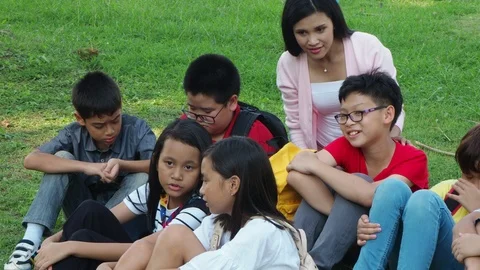 Group of student sitting on grass in park with their teacher Stock Footage 90276319