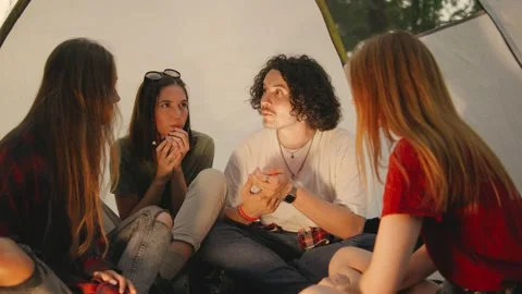 A group of student tourists gathers inside a tent at night, using a flashlight Stock Footage 285371653