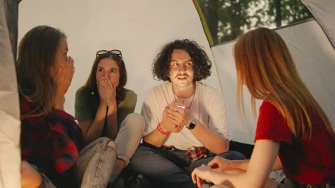 A group of student tourists gathers inside a tent at night, using a flashlight Stock Footage 285372033