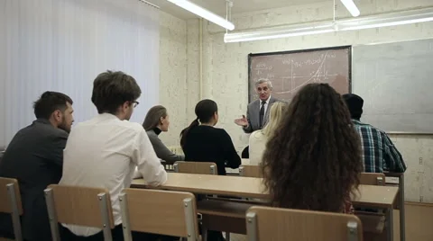 Group of students in a classroom, listening as their teacher holds a lecture. Stock Footage 44233465