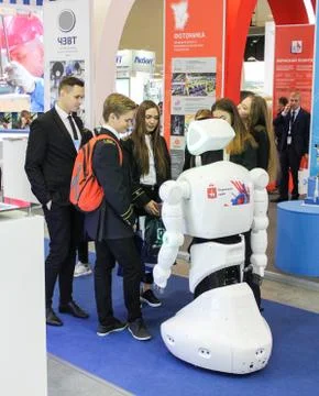 A group of students communicates with a robot. Stock Photos
