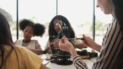 Group of students designing robotic arms with teacher in science classroom. Stock Photos