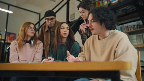 Group of students discussing projects in a library during a study session in the Stock Footage 337325805