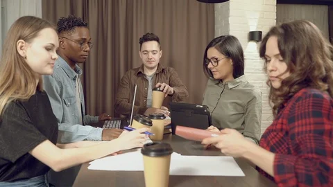 Group of students drinking coffee sharing books preparing for a seminar or exam Stock Footage 129496980