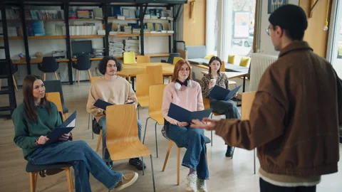 Group of students engaged in a learning session in a library while a teacher giv Stock Footage 337105025