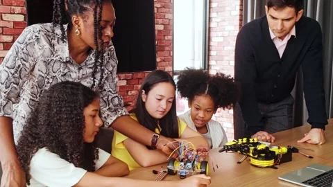 Group of students focus on building a robotics kit under teacher guidance. 動画素材 313478414