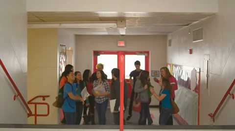 A group of students get excited before walking up some stairs into a hallway Stock Footage 33890581