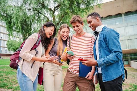 Group of students happily sharing content on social media using a cellphone app Stock Photos
