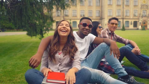 Group of students have fun in between classes on the lawn near the university Stock Footage 127913826