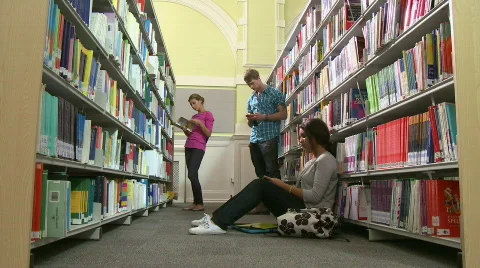 Group of students in library reading and playing with mobile phone Stock Footage 832456