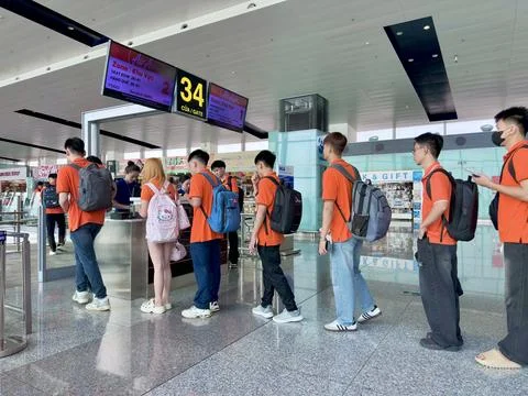 Group of students in orange uniforms queuing for boarding at departure gate Stock Photos