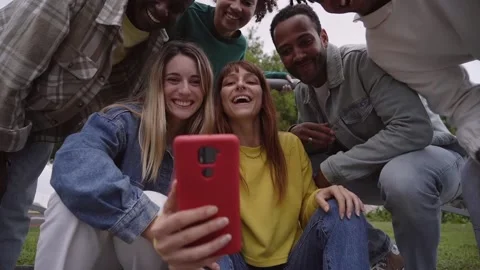 Group of students outside looking at mobile phone. Cheerful girl tells her Stock Footage 224750830
