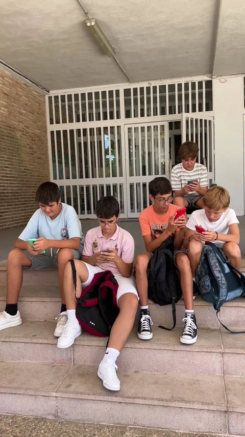 A group of students at the school gate using their cell phones. Stock Footage 248956779