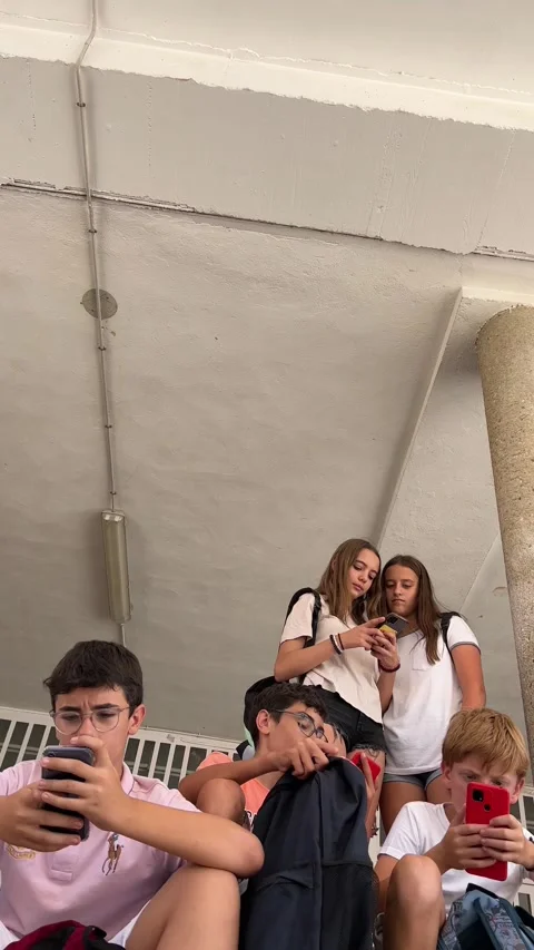 A group of students at the school gate using their cell phones. Stock Footage 248956891