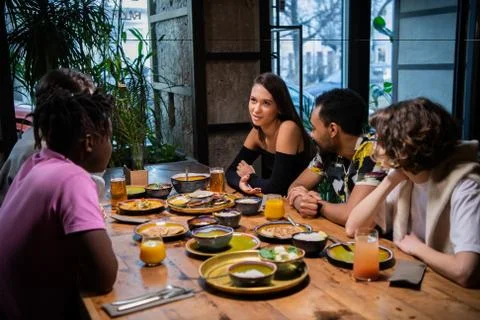 A group of students sitting at the table in a cafe, chatting, ha Stock Photos