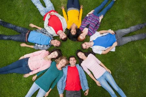 Group of students smiling at camera lying in circle on the grass on campus 写真素材