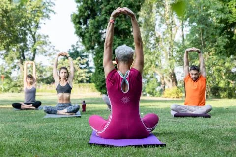 A group of students study under the guidance of their zen yoga master raising Stock Photos