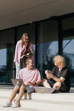 Group of students studying and using laptops outside a modern university Stock Photos