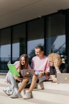 Group of students studying and using laptops outside a modern university Stock Photos