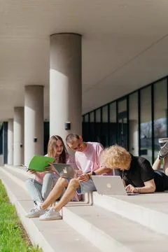 Group of students studying and using laptops outside a modern university Foto stock