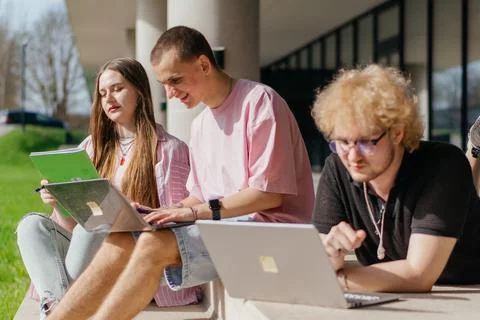 Group of students studying and using laptops outside a modern university Stock Photos