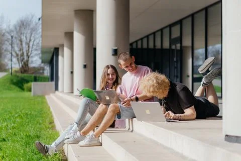 Group of students studying and using laptops outside a modern university Stock Photos