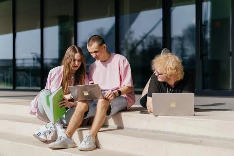 Group of students studying and using laptops outside a modern university Foto stock