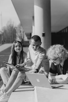 Group of students studying and using laptops outside a modern university Stock Photos
