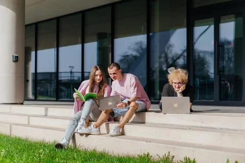 Group of students studying and using laptops outside a modern university Stock Photos