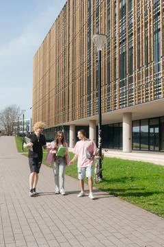 Group of students studying and using laptops outside a modern university 스톡 사진