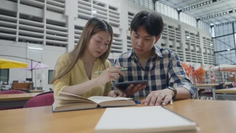 Group of students studying together in library. Two Asian students learning.. Stock Footage 334701902