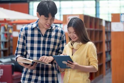 Group of students studying together in library. Two Asian students learning.. Stock Photos