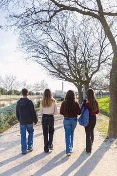 Group of students, with their backs, walking together along the park path Foto stock