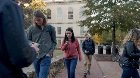 Group of students walking by each other all on their mobile phones on campus Video stock 104364546