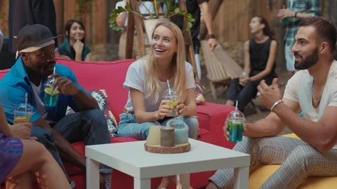 Group of stylish friendly people with drinks sitting together and talking Video stock 114927955