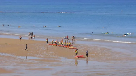 Group of a surf school repeating movements in front of their surf teacher Stock Footage 157539914