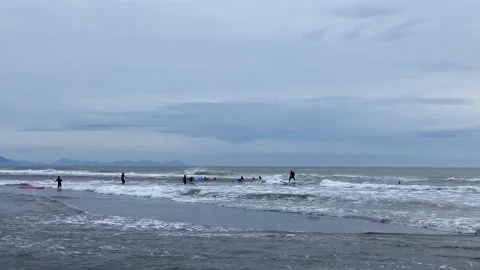 Group of surfers are learning to ride the small waves of the Pacific Ocean Video stock 141247009