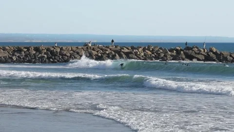 Group of Surfers Catching Waves with Breakwater in Background Stock Footage 310613600