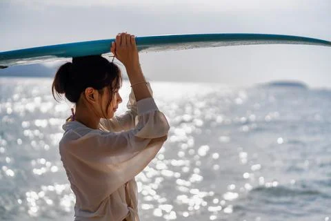 Group of surfers at sunset preparing for evening ride on ocean waves at beach Stock Photos
