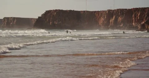 Group of surfers in wetsuits catch a wave in the Atlantic Ocean in Portugal. Stock Footage 248607913