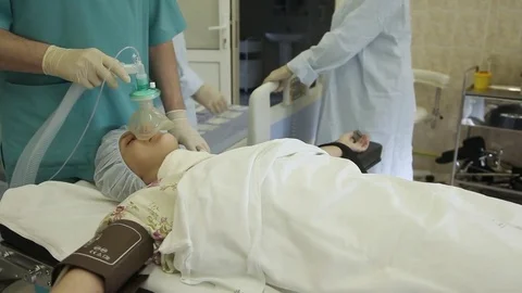 A group of surgeons shift the patient after surgery to a bed for transportation. Stock Footage 81999439