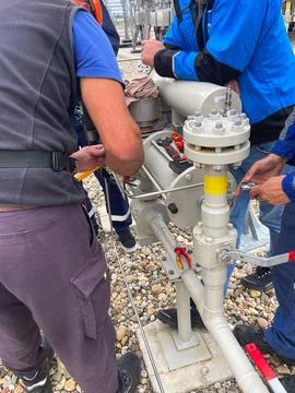 Group of technicians working on a pressurized industrial pipeline outdoors Foto stock