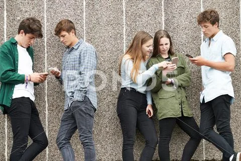 Group Of Teenagers Sharing Text Message On Mobile Phones Stock Photos
